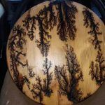 Wood plaque with black, tree-like dendrites.