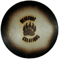 Round wooden coaster with charred edges, logo reads 