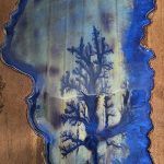 Blue resin art on wood, with silhouetted tree design and rippled effect.