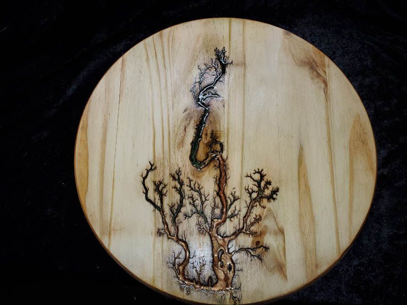 Wooden circle with lightning-like fractal design; dark burnt wood pattern on light wood, resembling a tree.