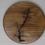 Wooden circle with tree design burned into it.