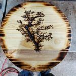 Round wood art piece with scorched edge, a tree design in the center created by Lichtenberg burning.