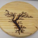 Wooden disc with a tree burned into the surface.