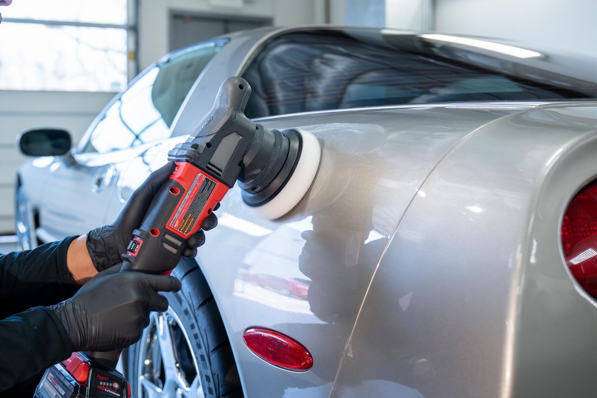 A person is polishing a car with a machine.