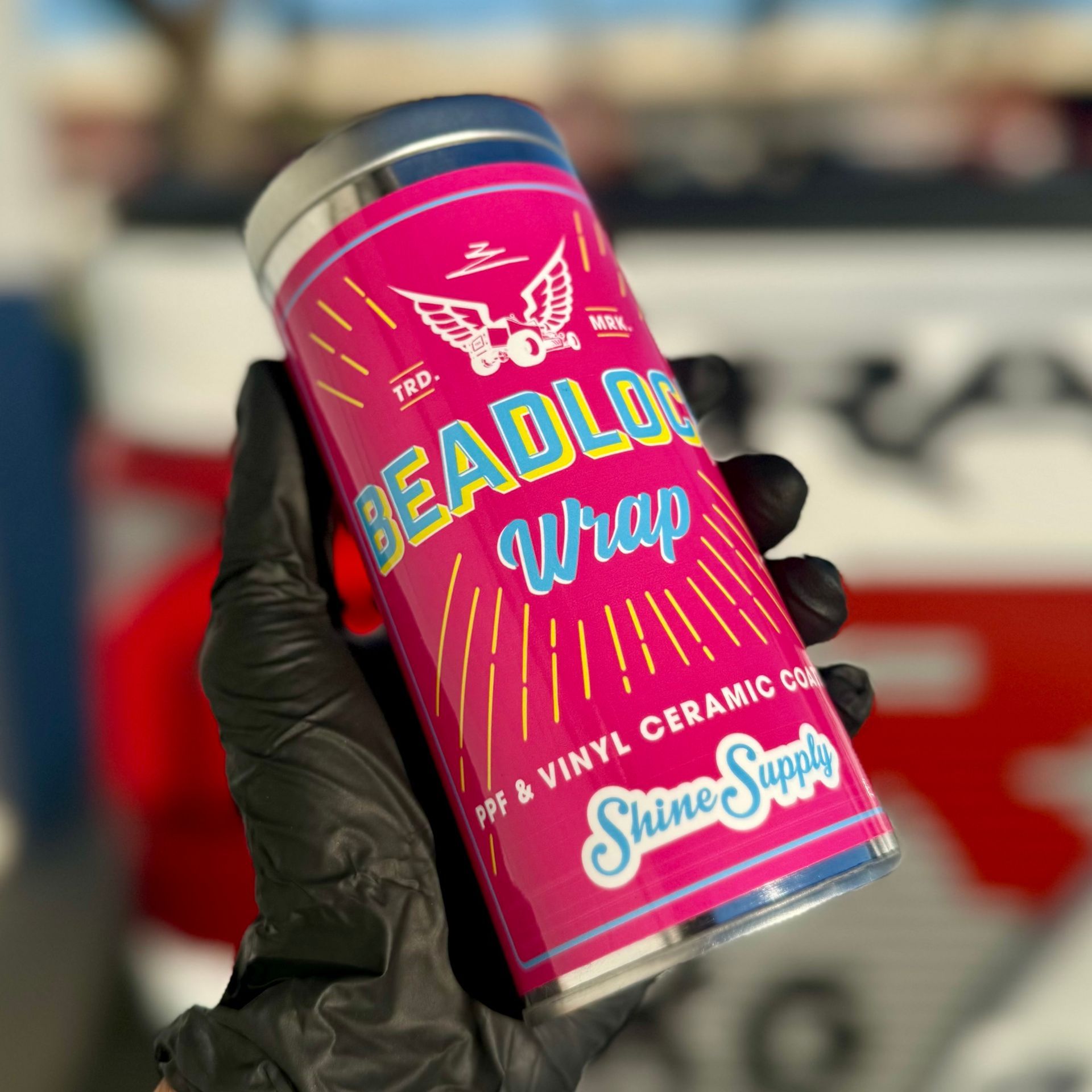 Blue car hood with water droplets; red and pink lights reflect.