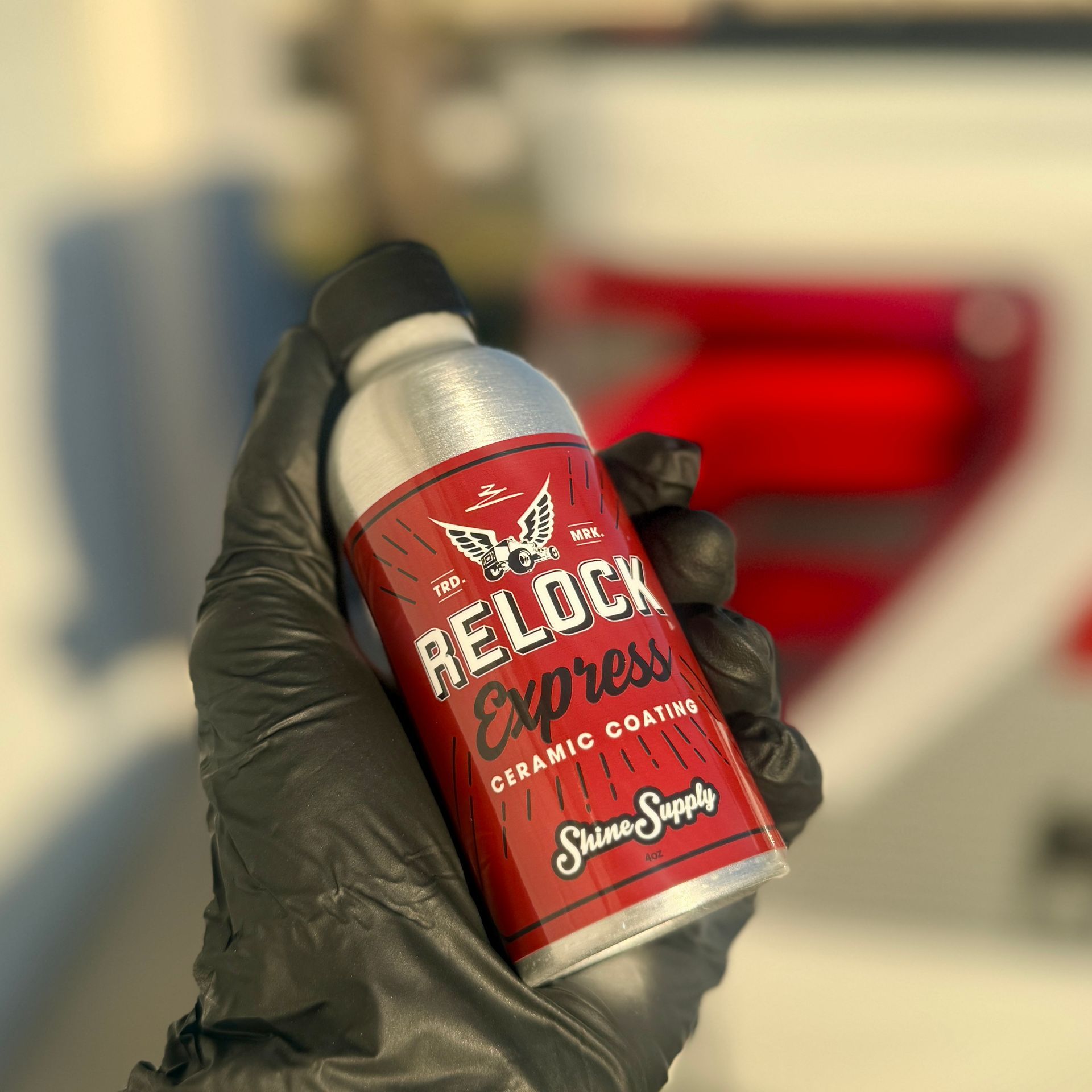 Hand in black glove holding a silver and red RELOCK Express ceramic coating spray bottle.