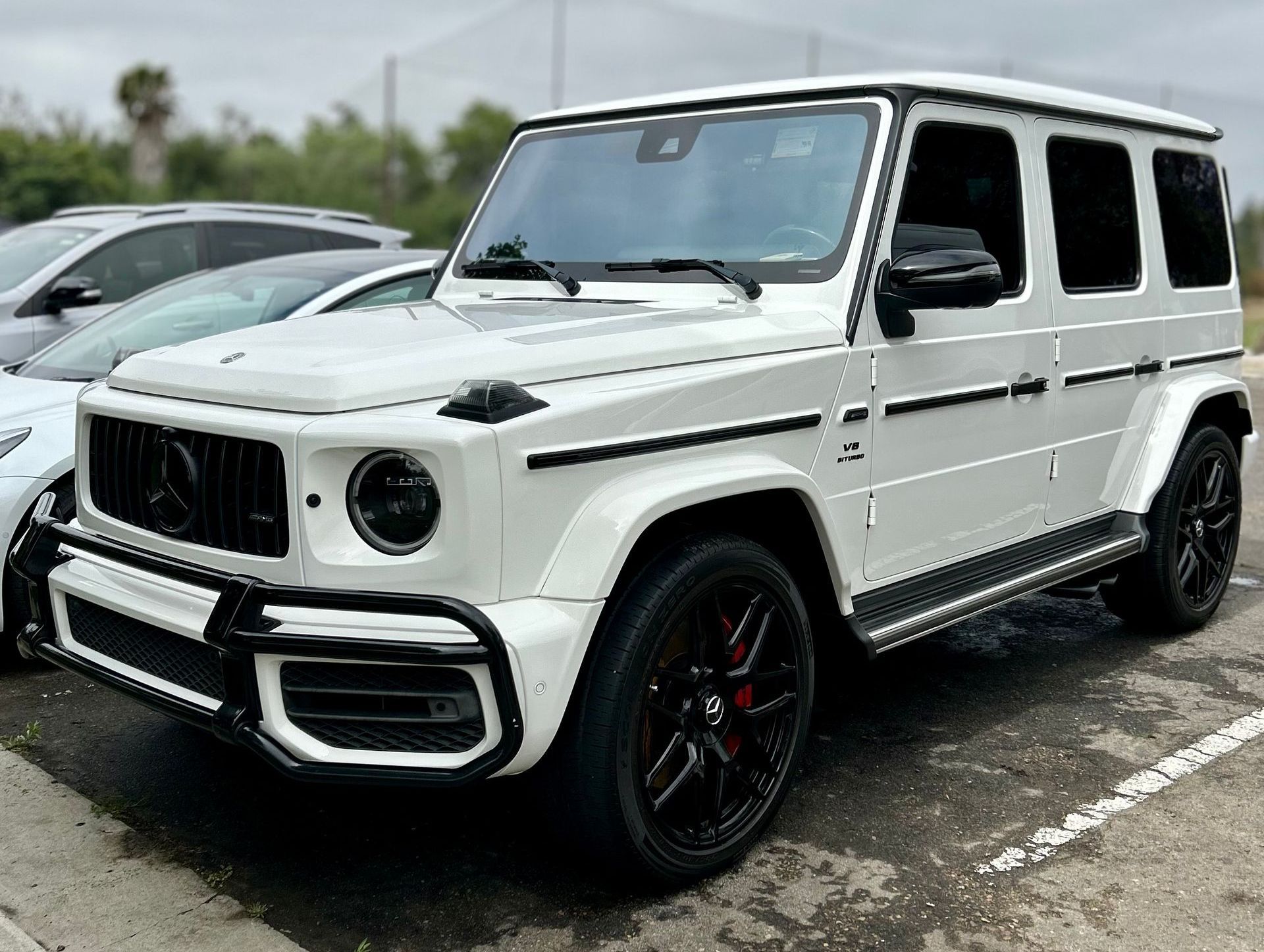 A white mercedes benz g63 amg is parked in a parking lot.