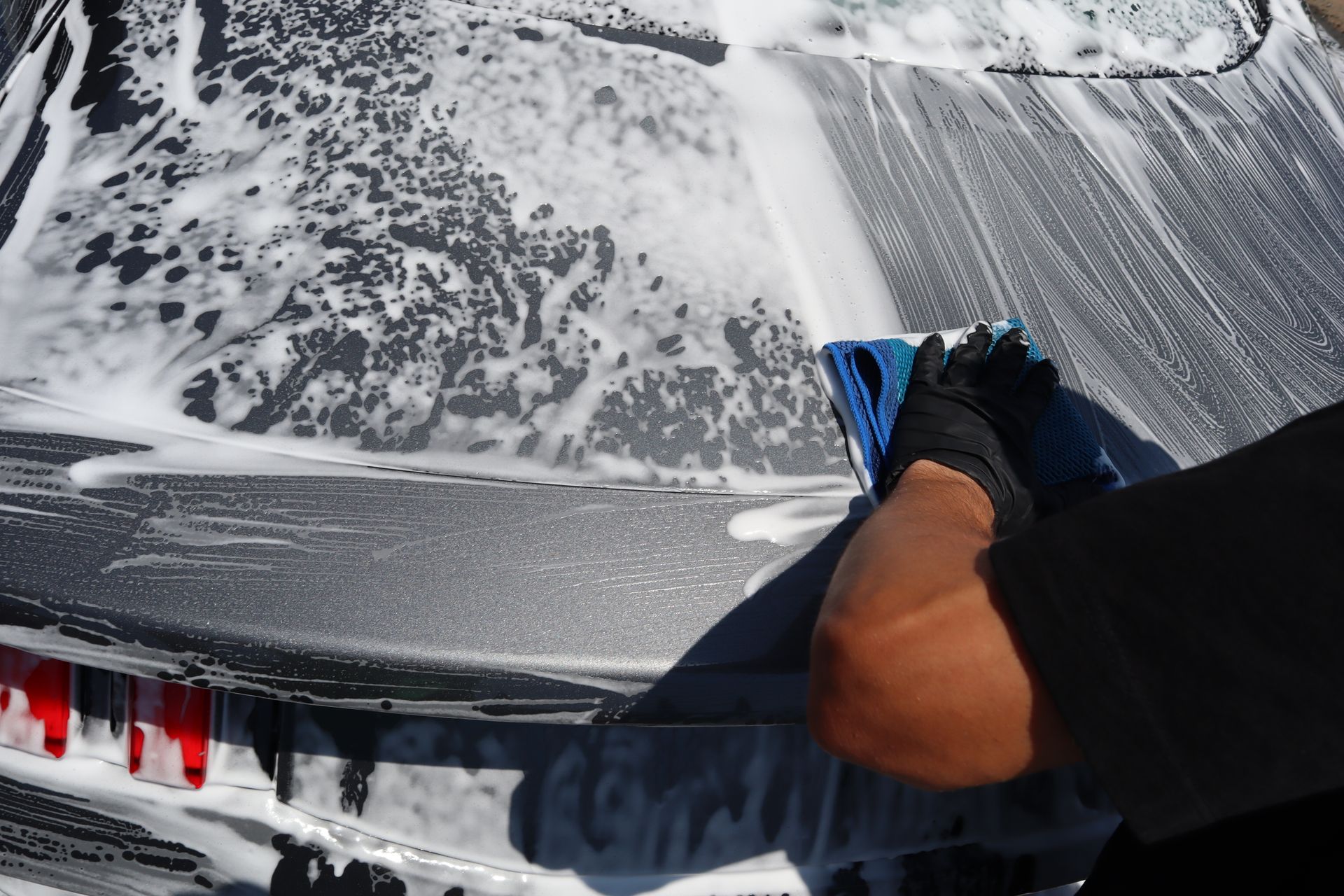 A person is washing a car with a towel and soap.