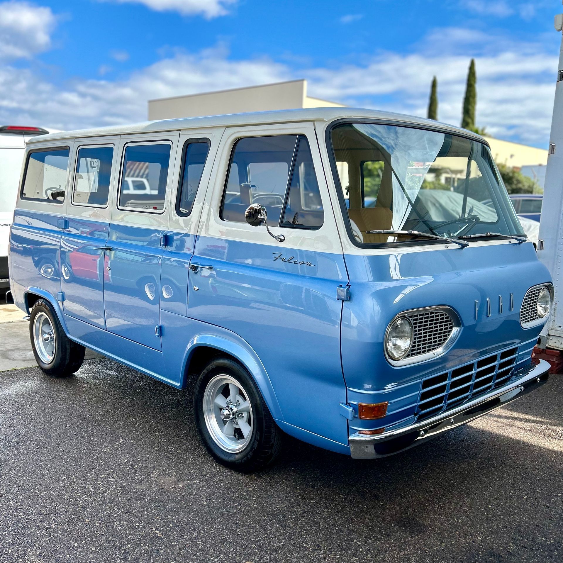 A blue and white van is parked on the side of the road.