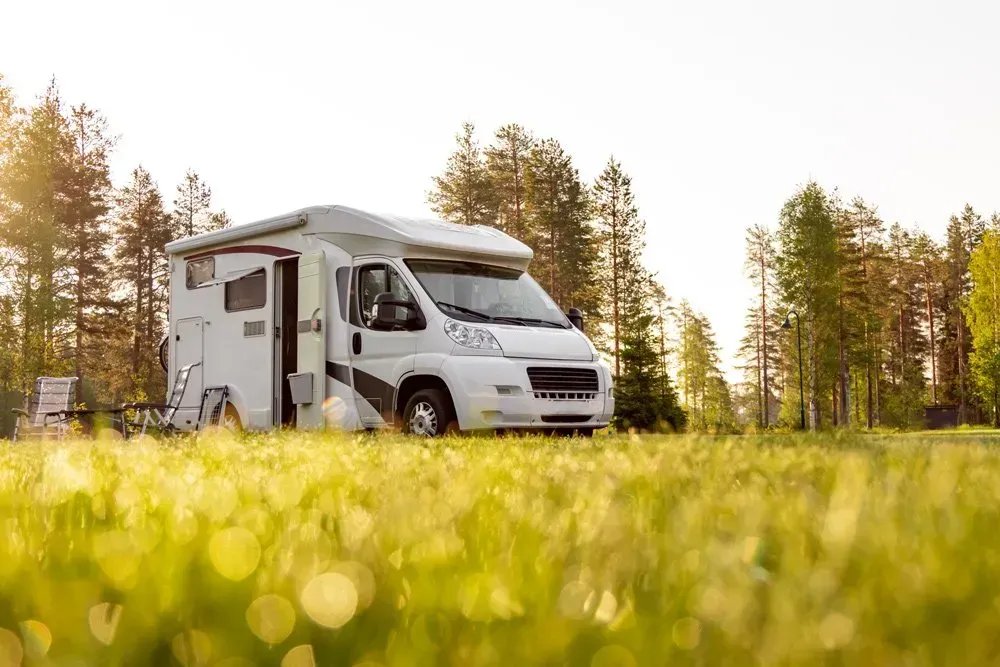 A White Rv Is Parked In A Grassy Field — Affordable Caravan Repairs in Bundaberg, QLD
