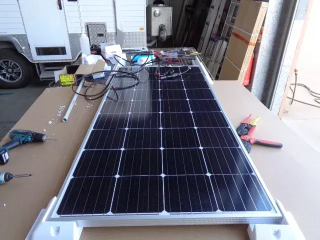 A Solar Panel Is On A Table In Front Of A Trailer — Affordable Caravan Repairs in Bundaberg, QLD