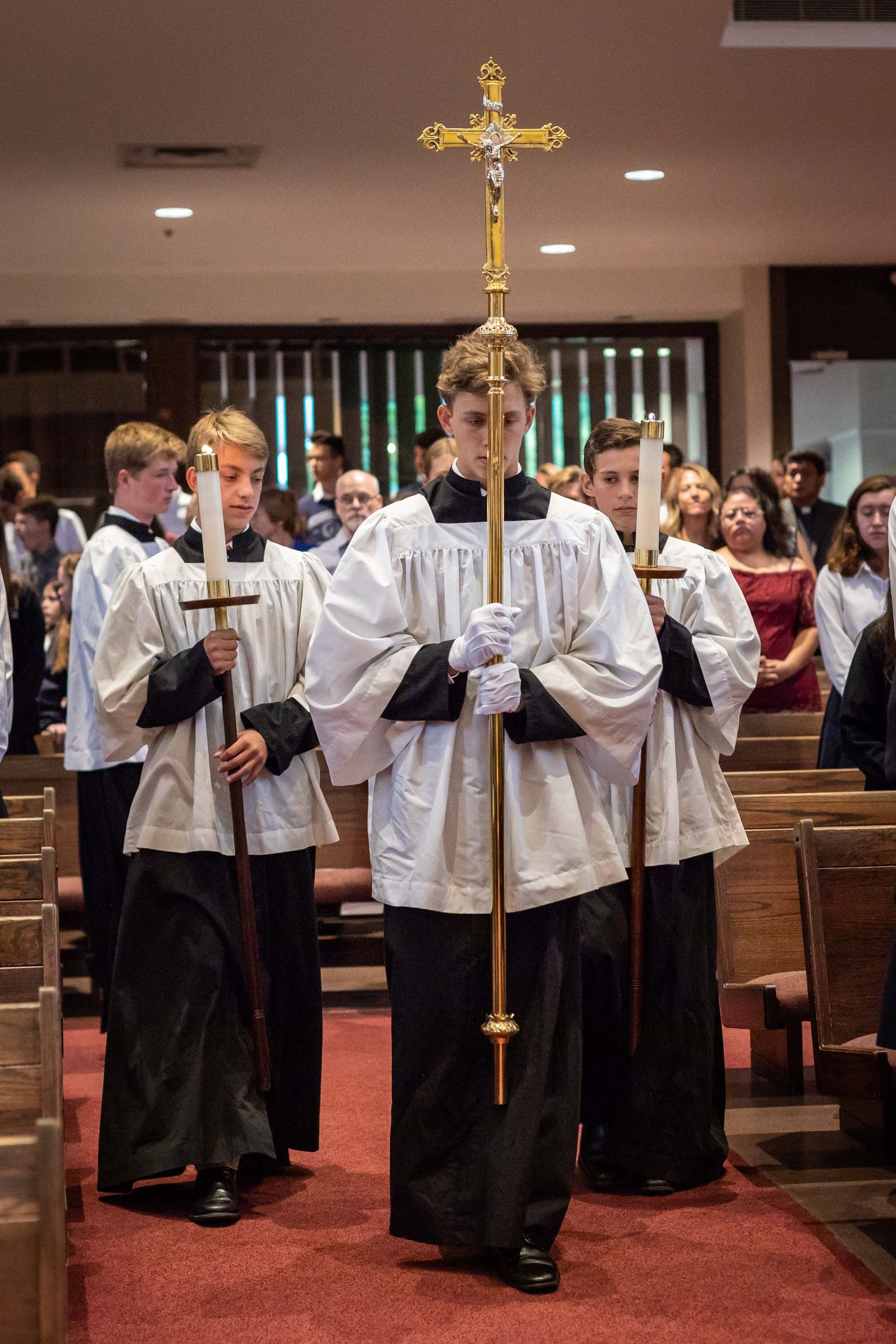 A group of priests carrying candles and a cross in a church