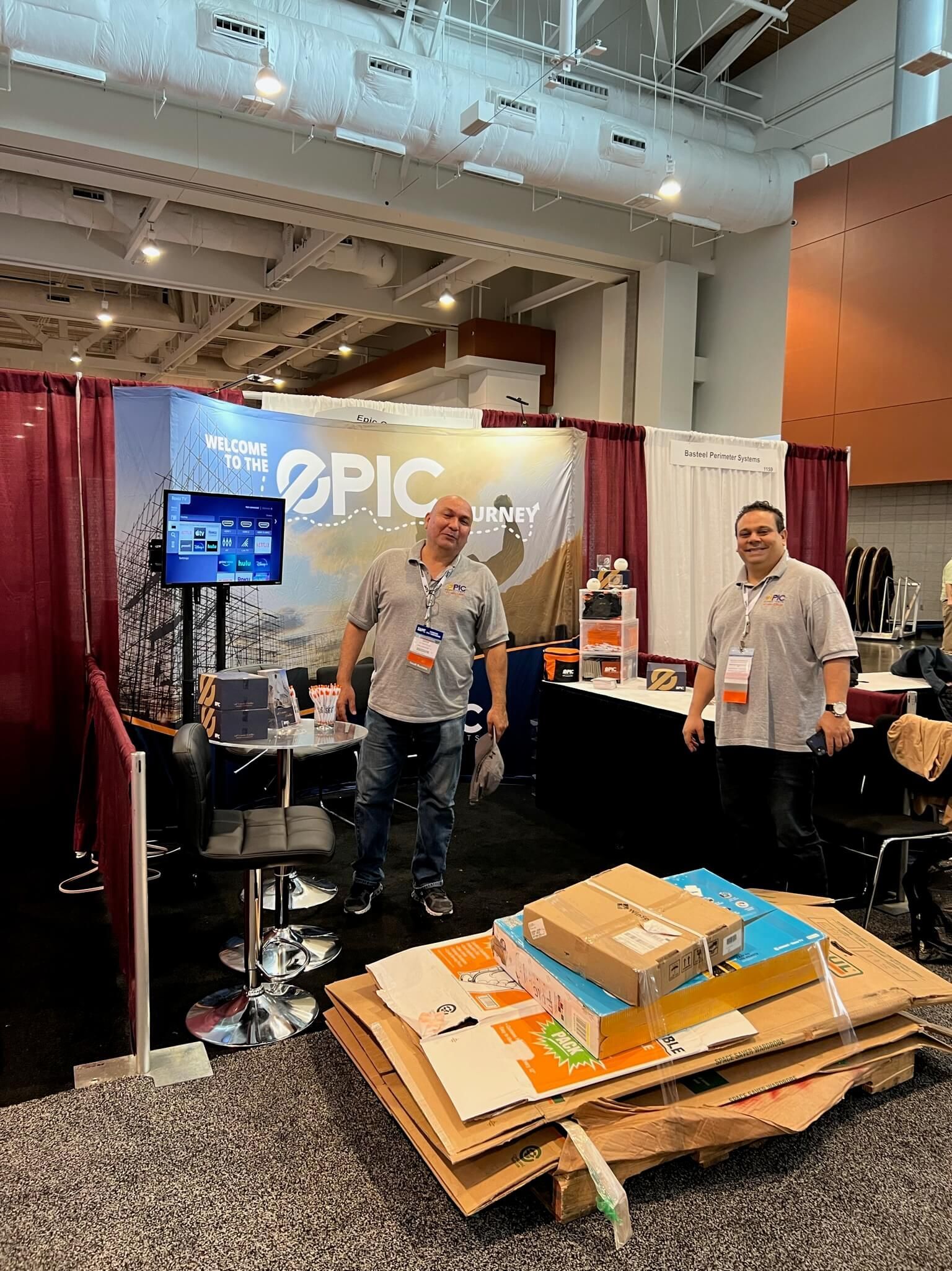 Two men standing in front of a sign that says epic