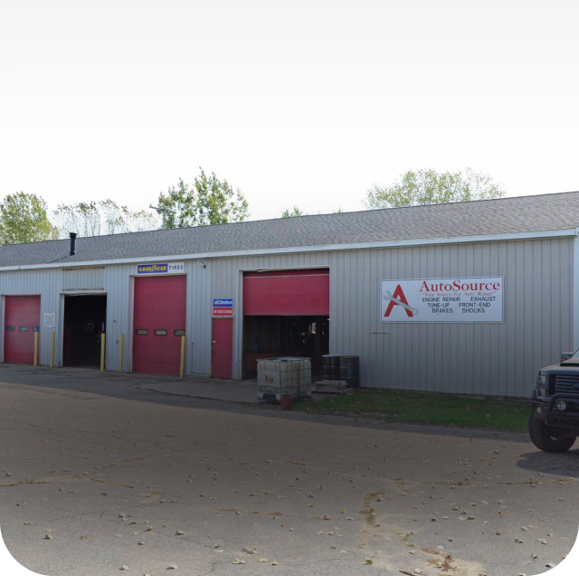 A gray auto repair shop with red doors and a sign that reads 