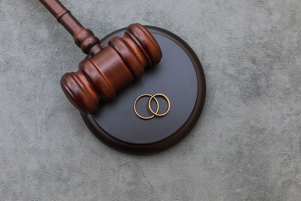 A pair of wedding rings sitting on top of a wooden judge 's gavel.