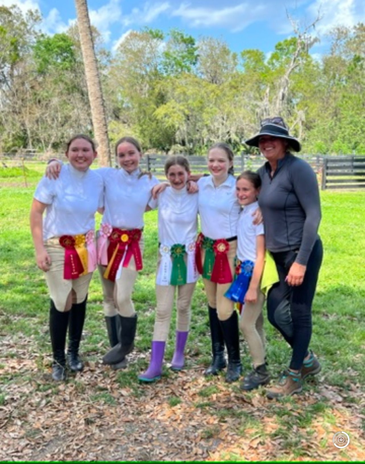 A group of young girls are posing for a picture with ribbons around their waists.