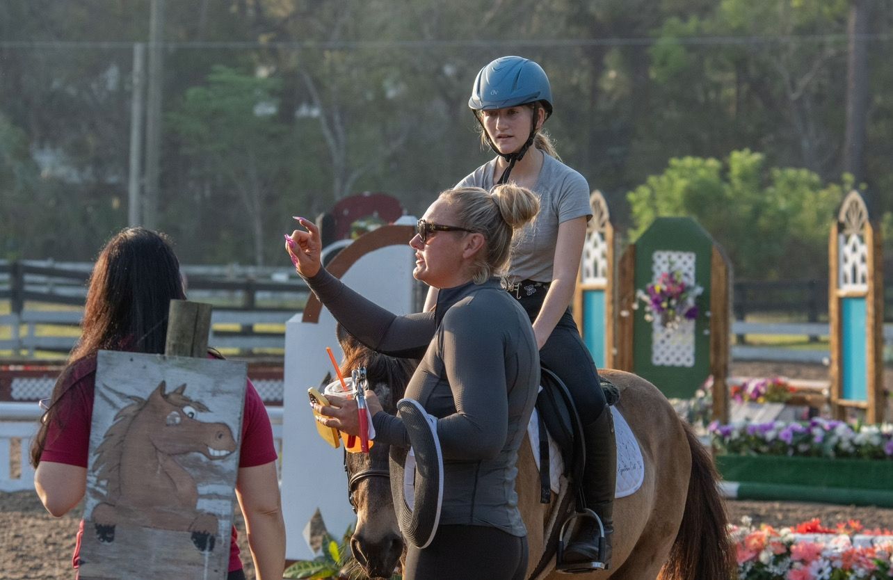 A woman is teaching a young girl how to ride a horse.