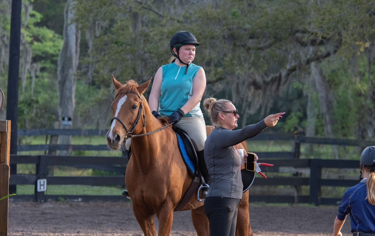 A woman is teaching a young girl how to ride a horse.