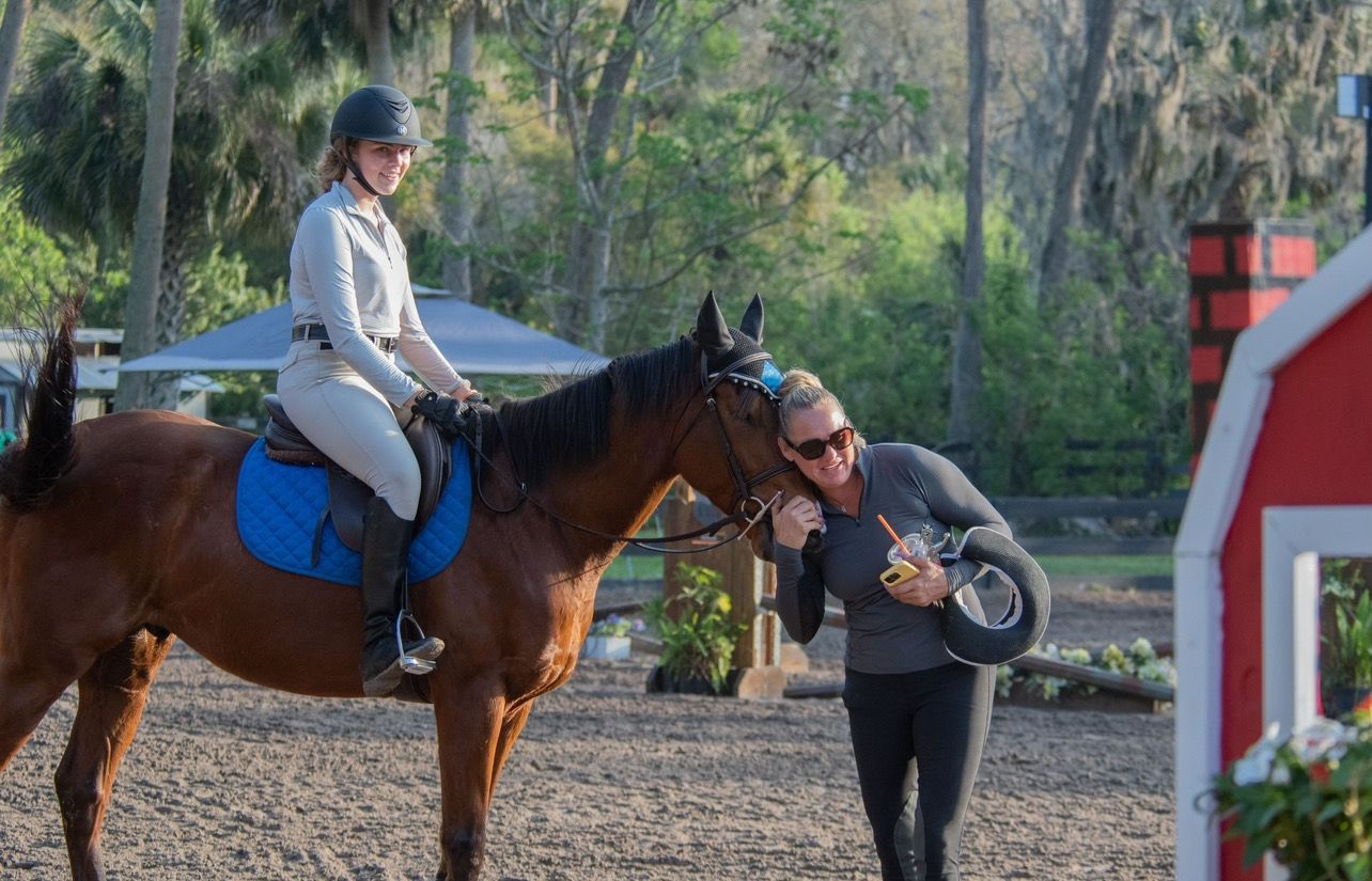 A woman is riding a horse while a man stands next to it.