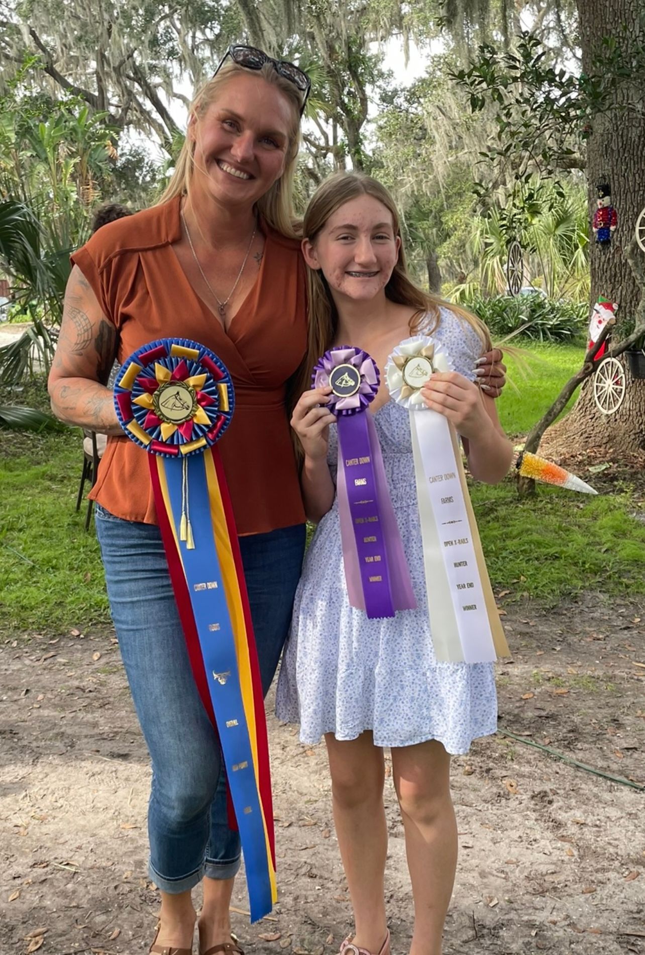 A woman and a girl are standing next to each other holding ribbons.