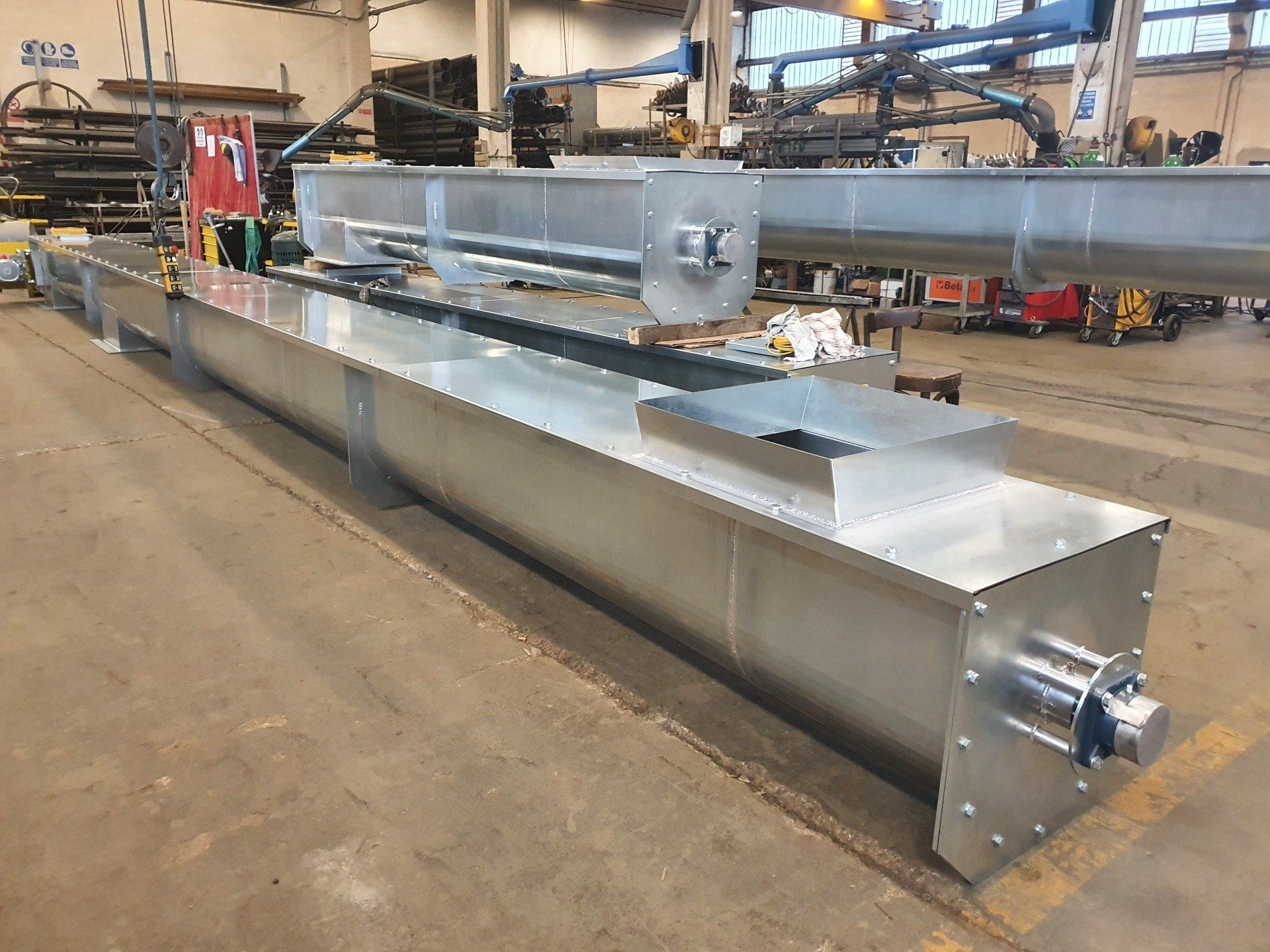 Un grande tubo di metallo è appoggiato a terra in una fabbrica.