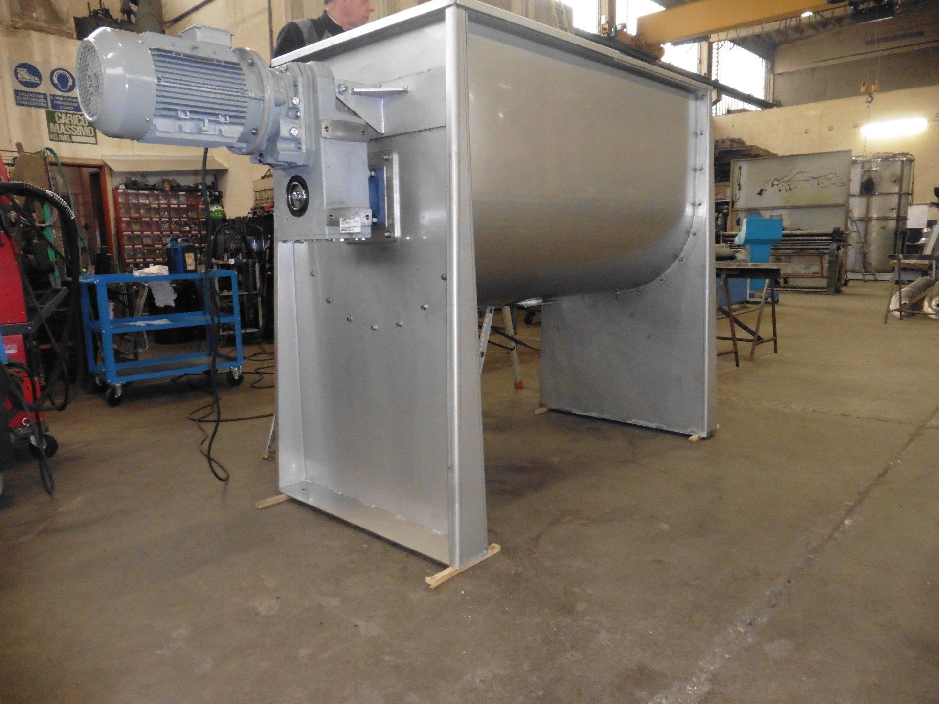 Un grande miscelatore in acciaio inossidabile è parcheggiato in un magazzino.