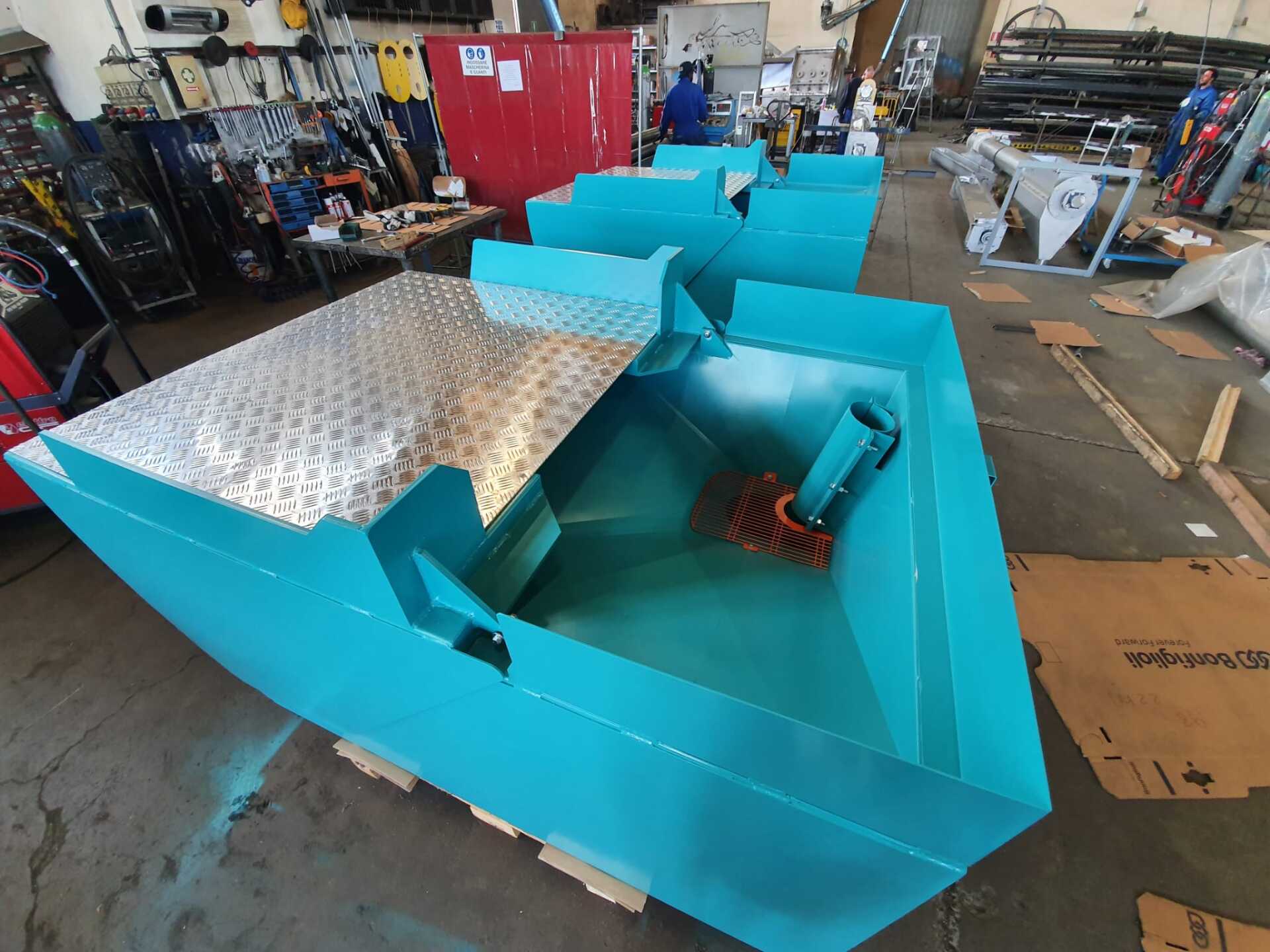 Una barca blu è appoggiata su un pallet in una fabbrica.