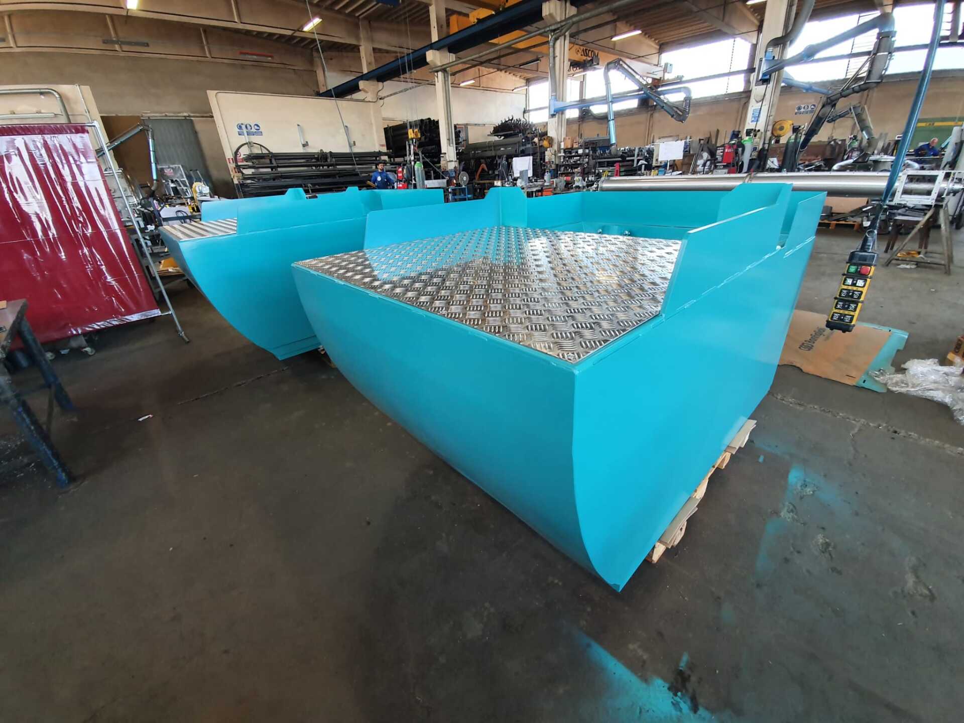 Un grande container blu è appoggiato sul pavimento di una fabbrica.