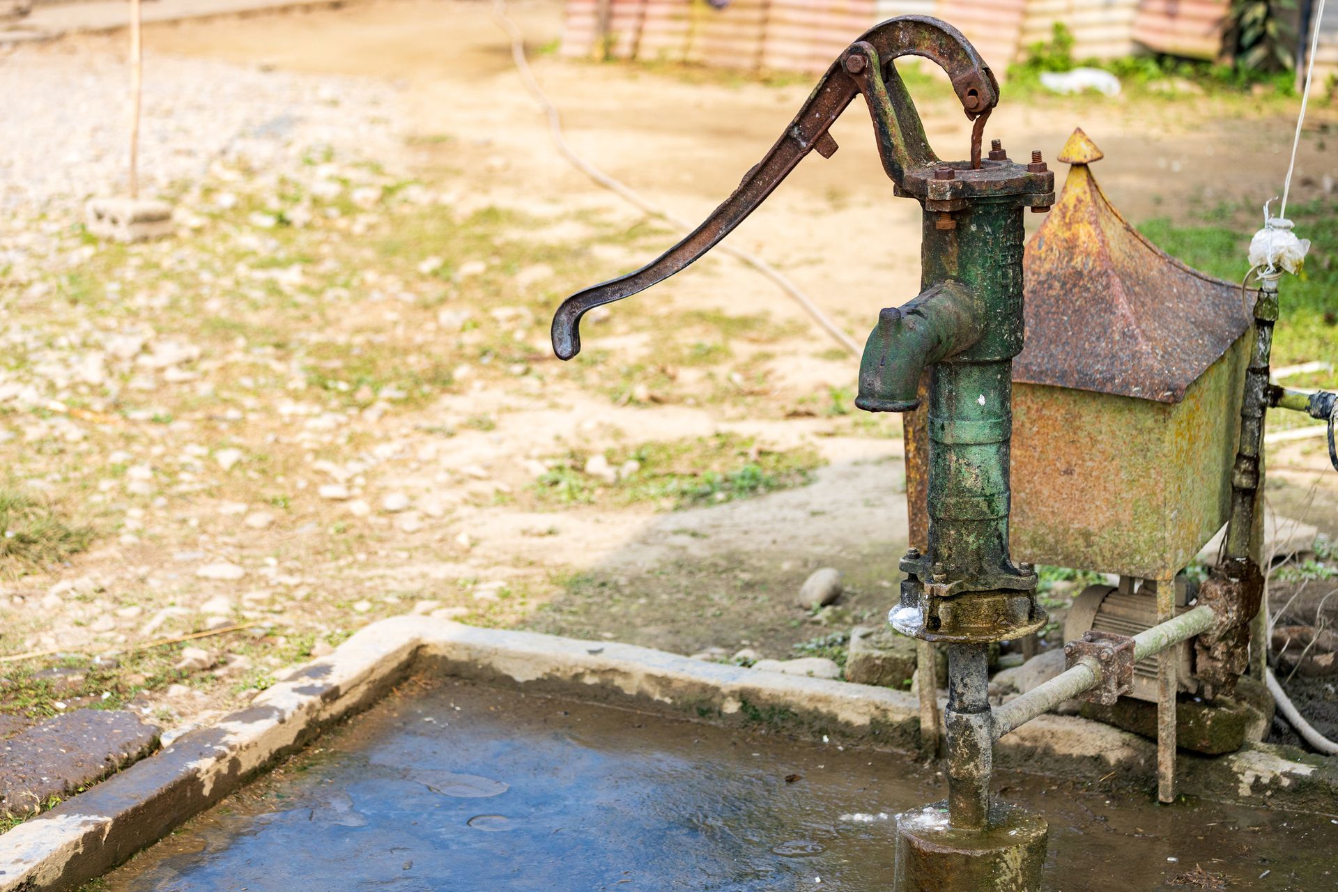 An old water pump is pumping water into a pool.