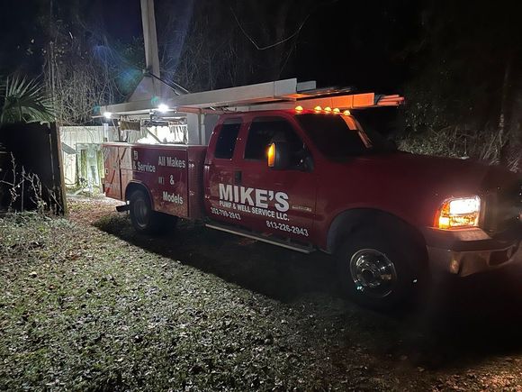 A red mike 's truck is parked in a gravel lot at night.