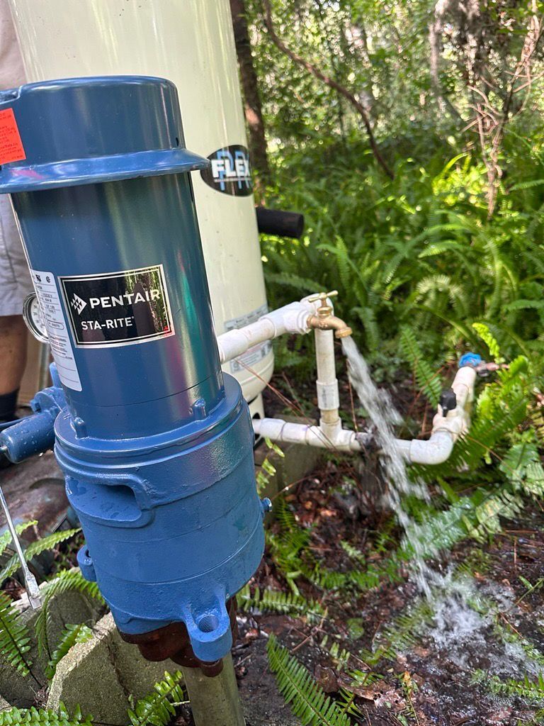 A person is working on a water pump in the woods.