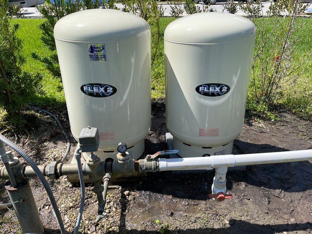 Two white water tanks are sitting next to each other on the ground.