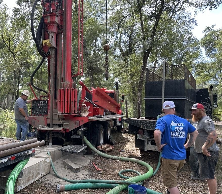 A group of men are working on a drilling rig in a field.