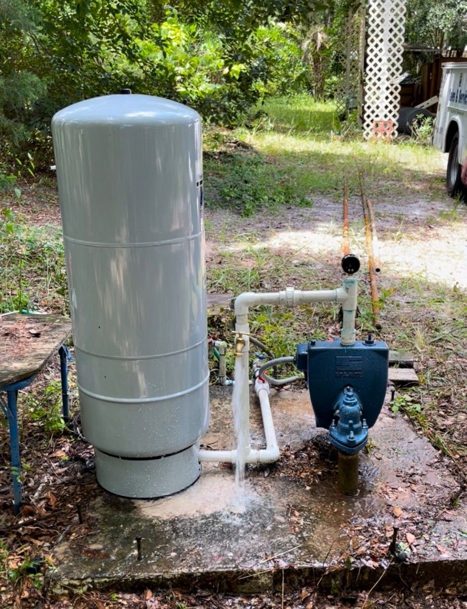 Outdoor water well system featuring a large Gray pressure tank connected