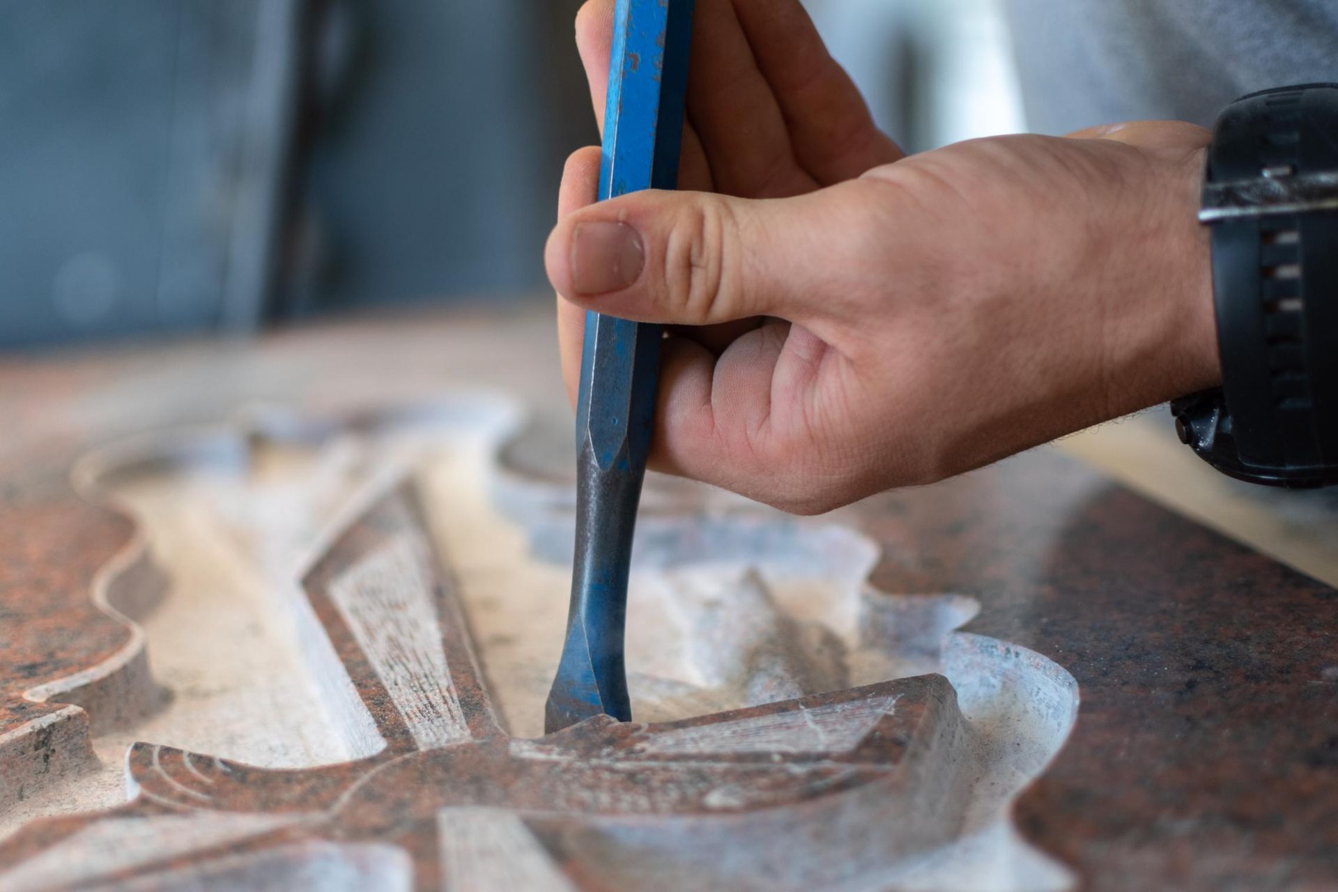 Person using a chisel to carve a detailed design into a stone surface.