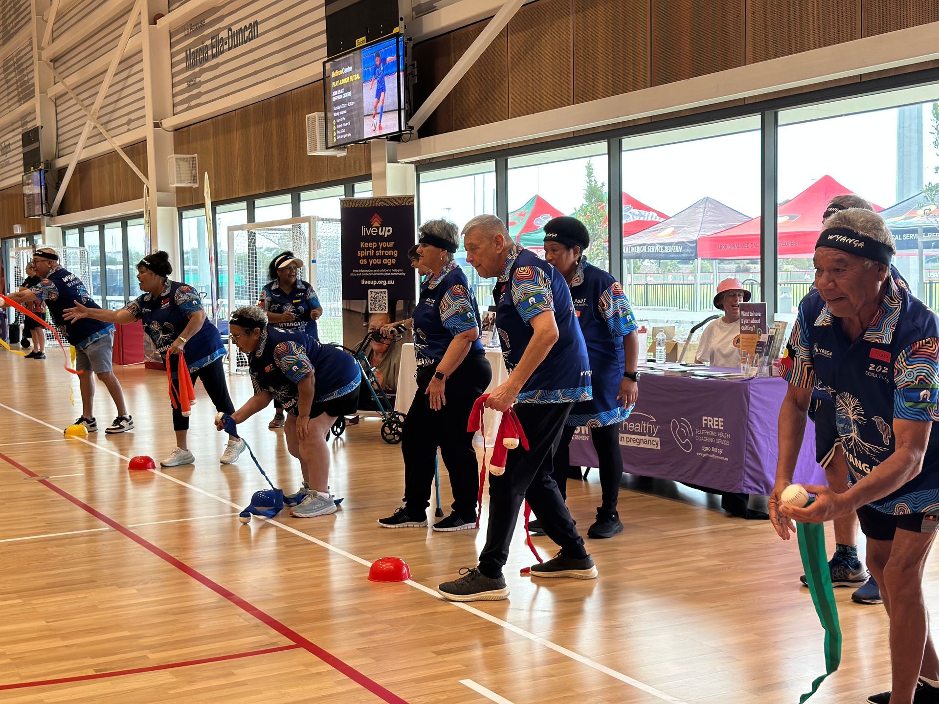 A group of people are playing a game of bowling on a wooden floor.