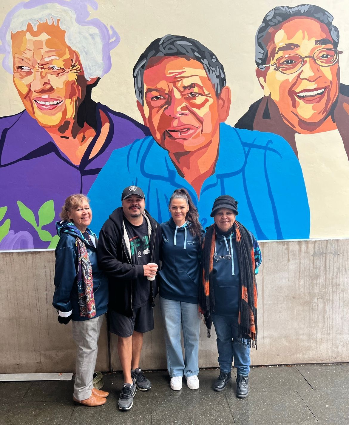 A group of people standing in front of a mural