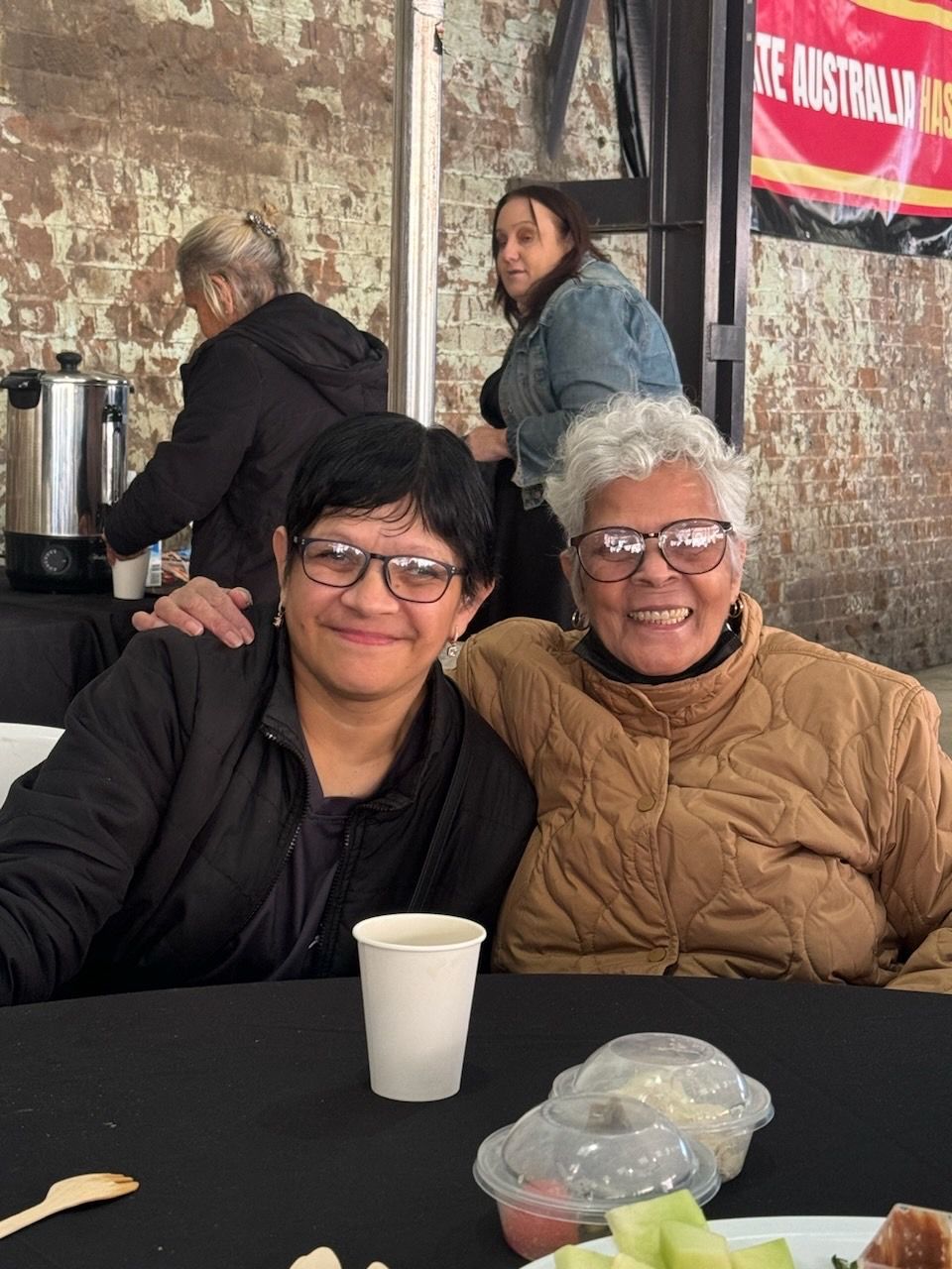 Two women are posing for a picture while sitting at a table