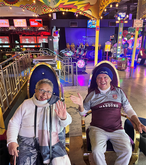 A man and a woman are sitting in chairs in an amusement park.