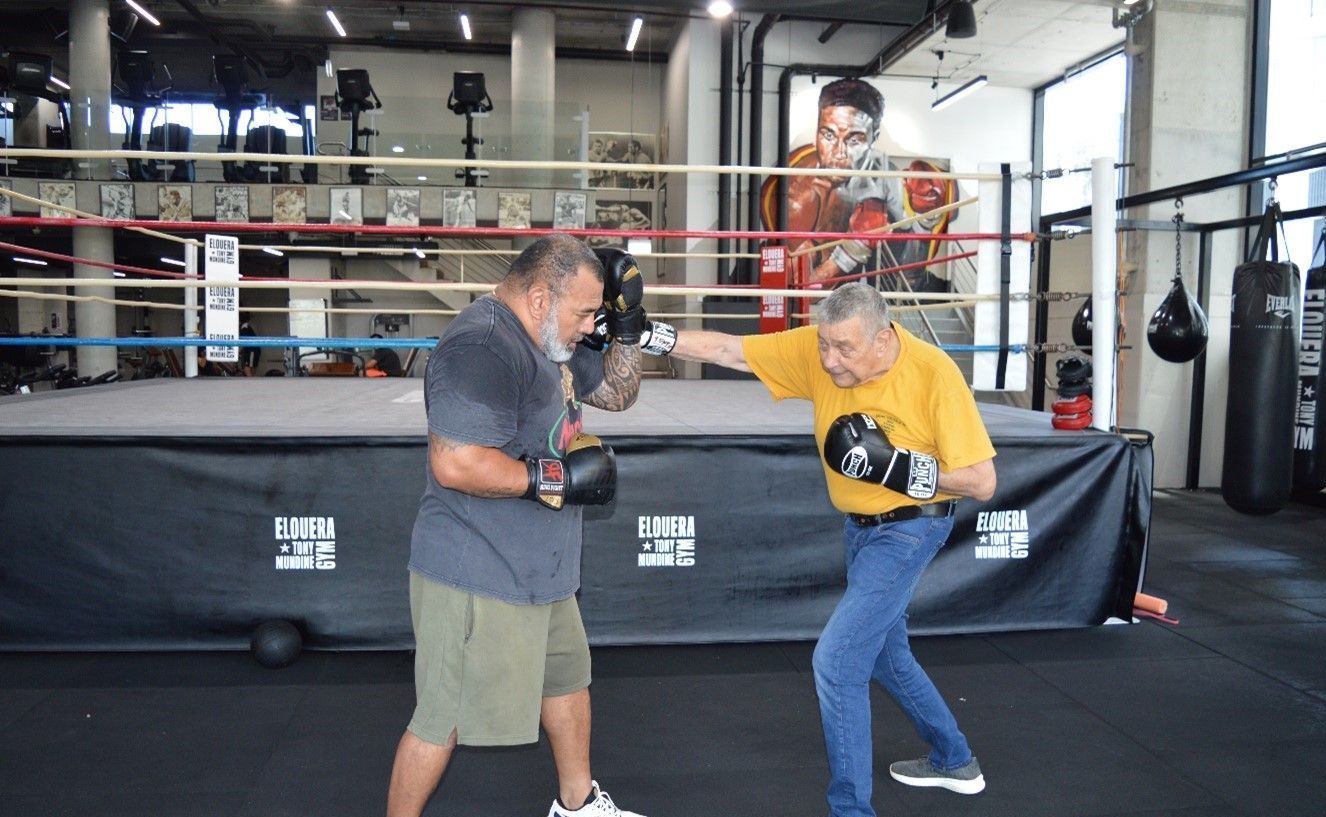 Two men are boxing in a boxing ring in a gym.