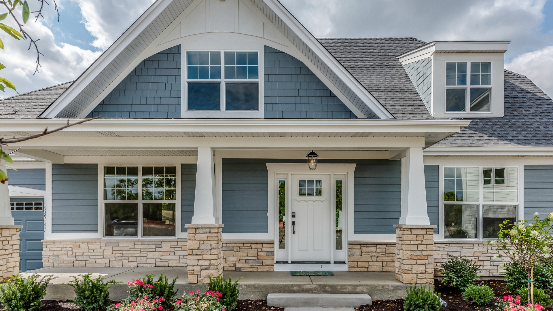 Blue and white house with stone accents, white pillars, and a welcoming porch.