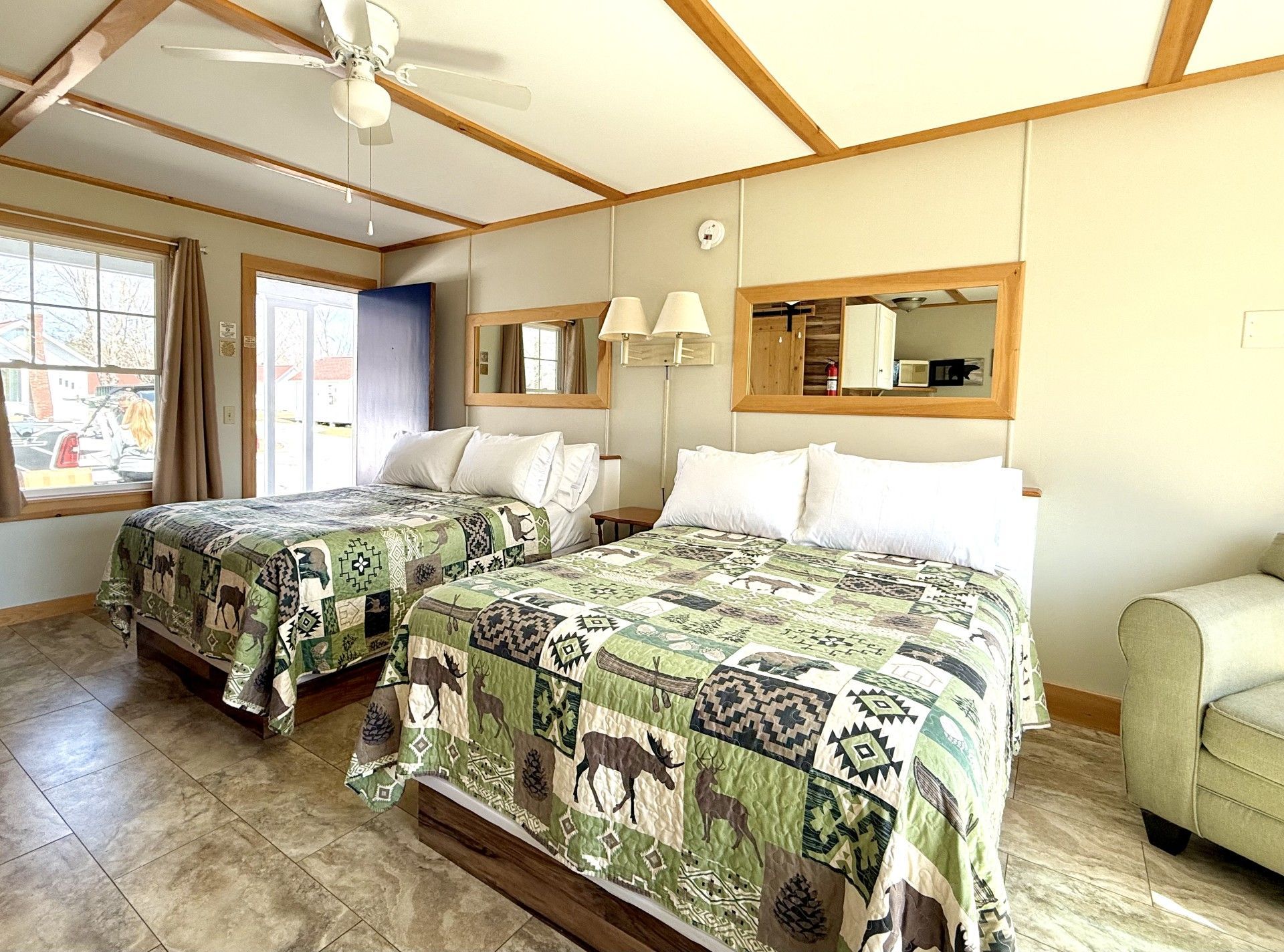 A hotel room with two beds , a couch , and a ceiling fan.