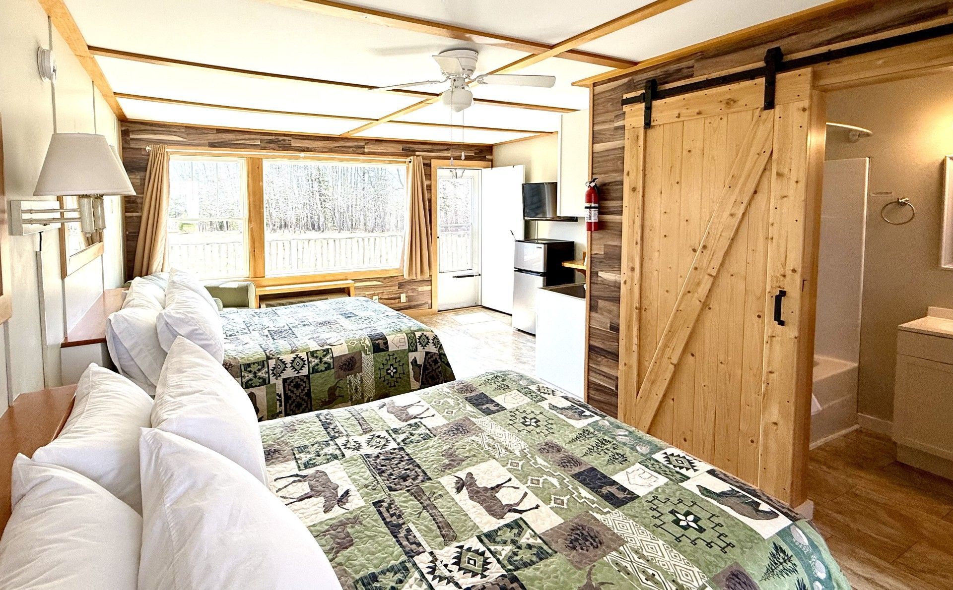 A hotel room with two beds and a sliding barn door.