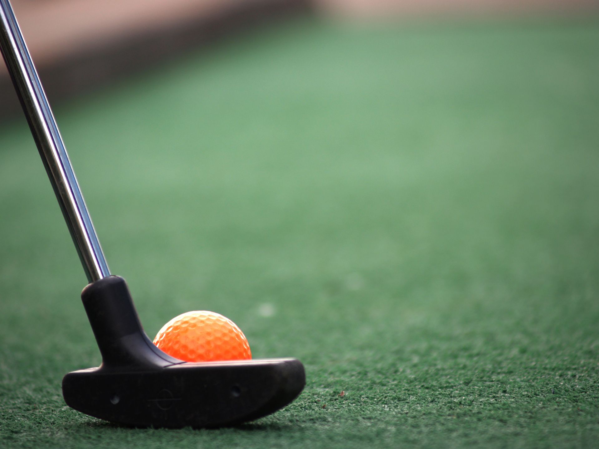 A close up of a golf club and ball on a golf course.