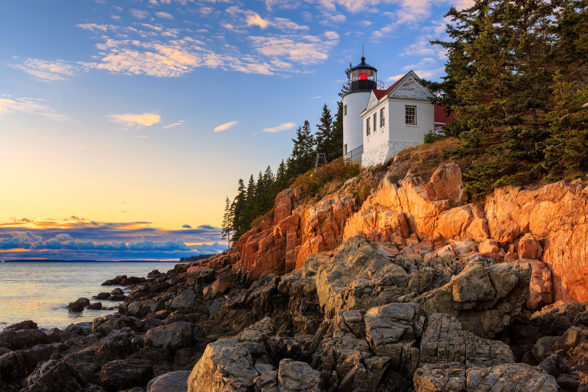 A lighthouse is sitting on top of a rocky cliff overlooking the ocean.