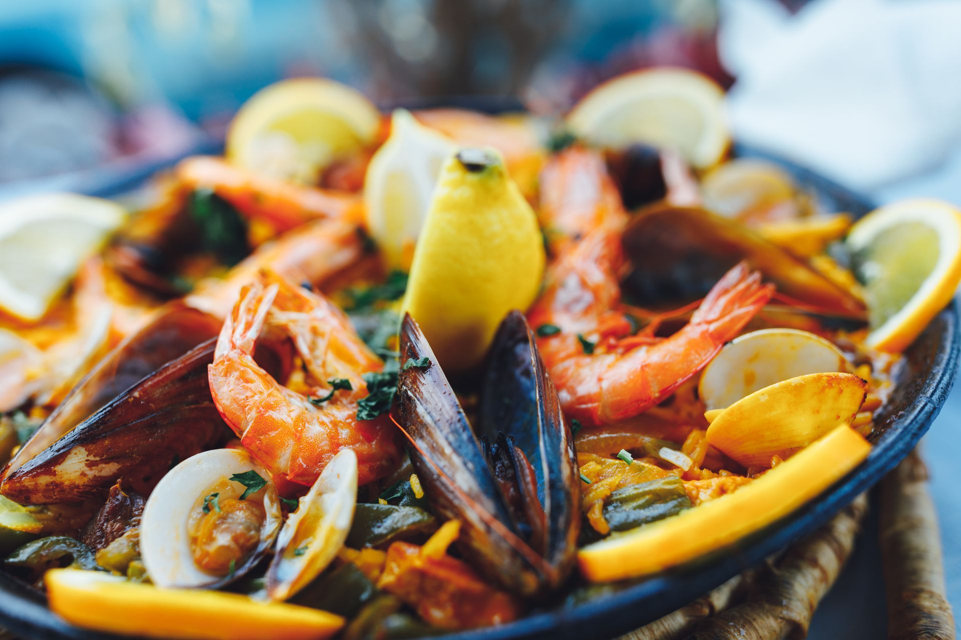 A close up of a paella with shrimp , mussels , eggs and lemon slices.