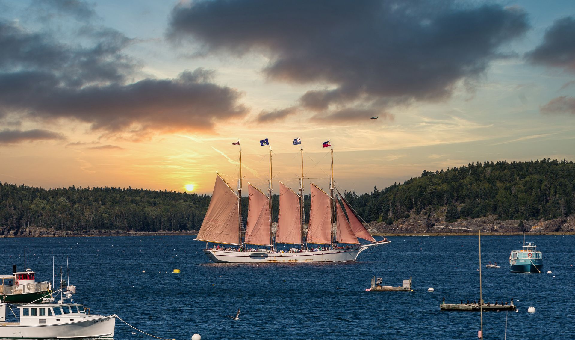 A sailboat is floating on top of a body of water at sunset.