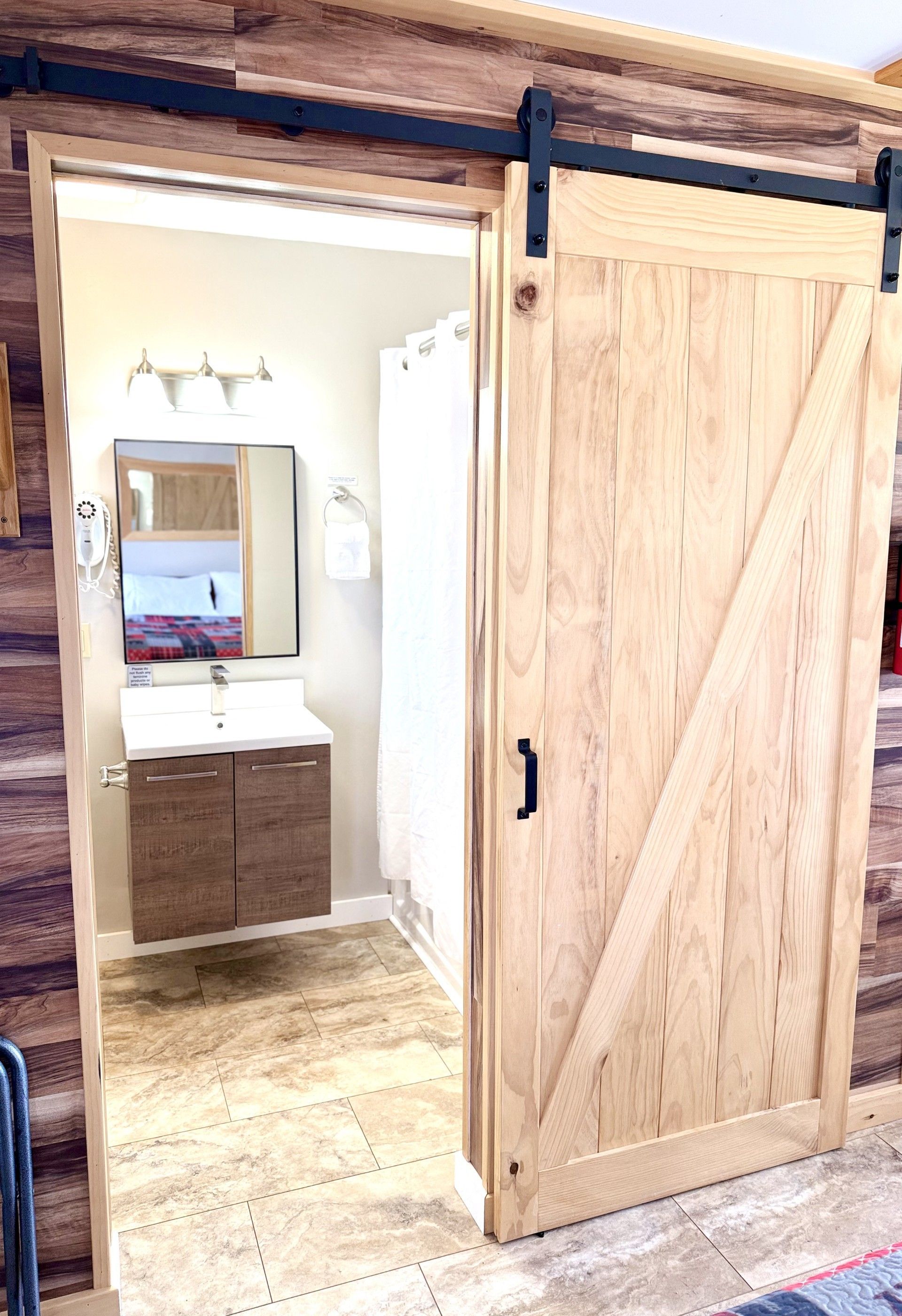A bathroom with a sliding barn door and a sink.