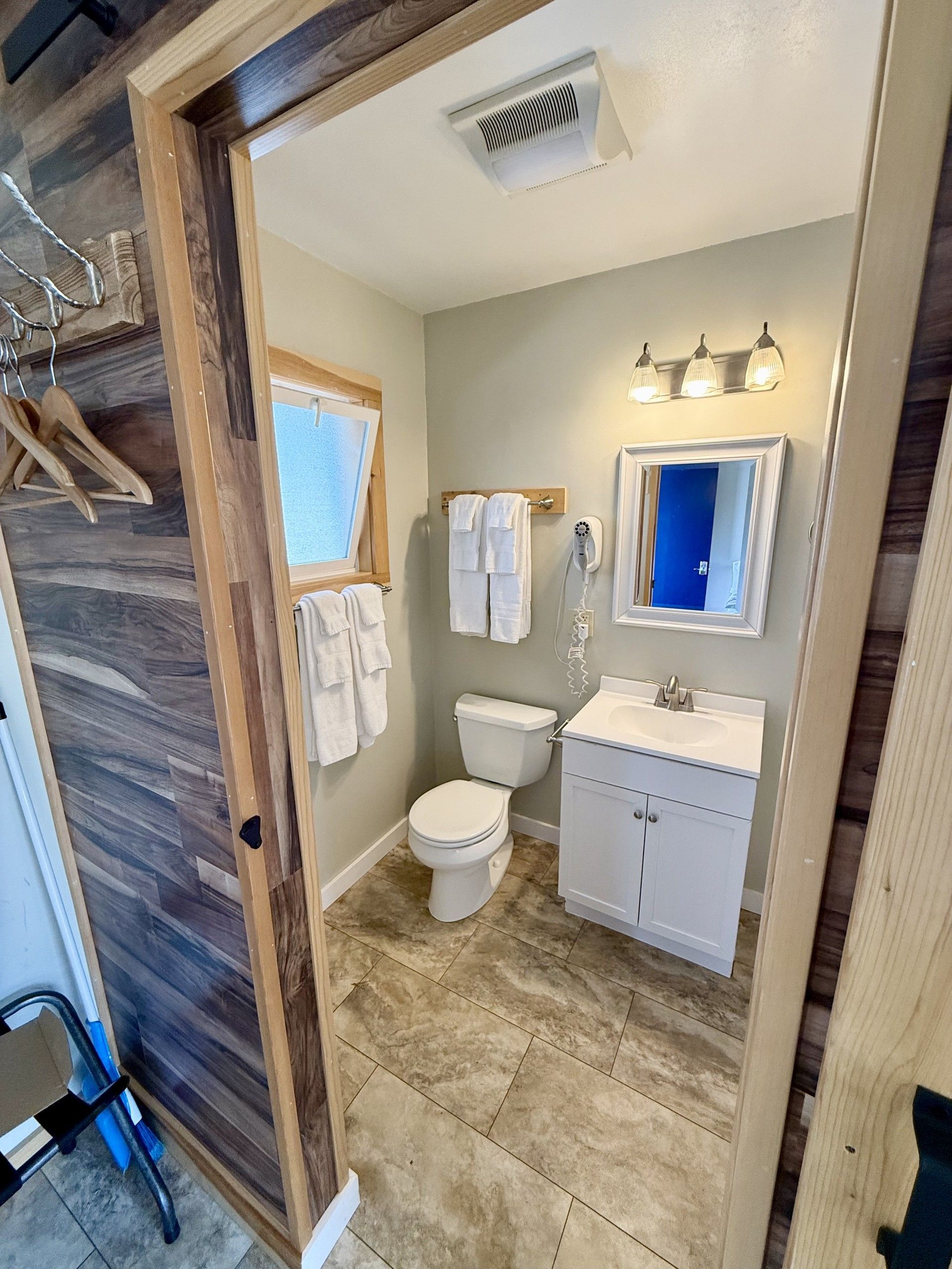 A bathroom with a toilet , sink and mirror.