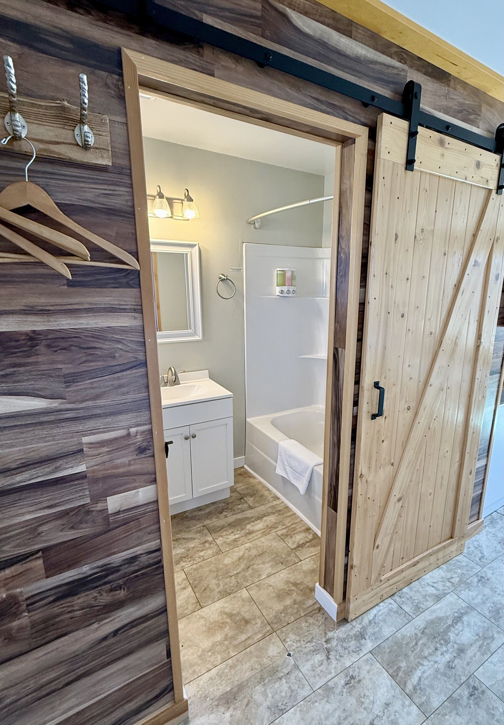 A bathroom with a sliding barn door leading to it.